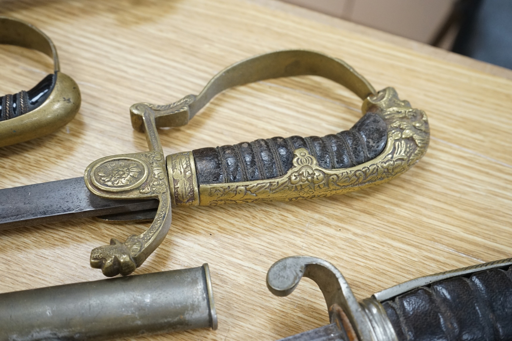 An Imperial German presentation infantry officer’s sword dated 1919/20, another similar with plain blade and brass stirrup hilt, another similar, plain in steel scabbard, a Wilkinson masonic sword probably circa 1950, a